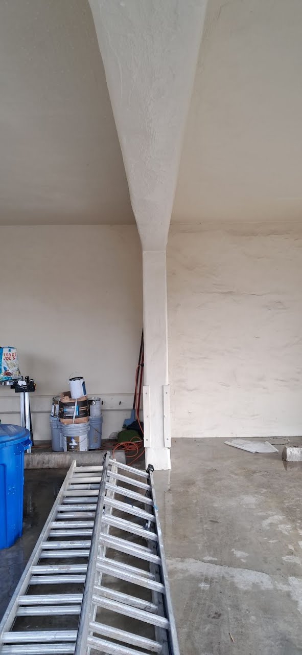 A ladder on the floor of a house with white walls and an arch